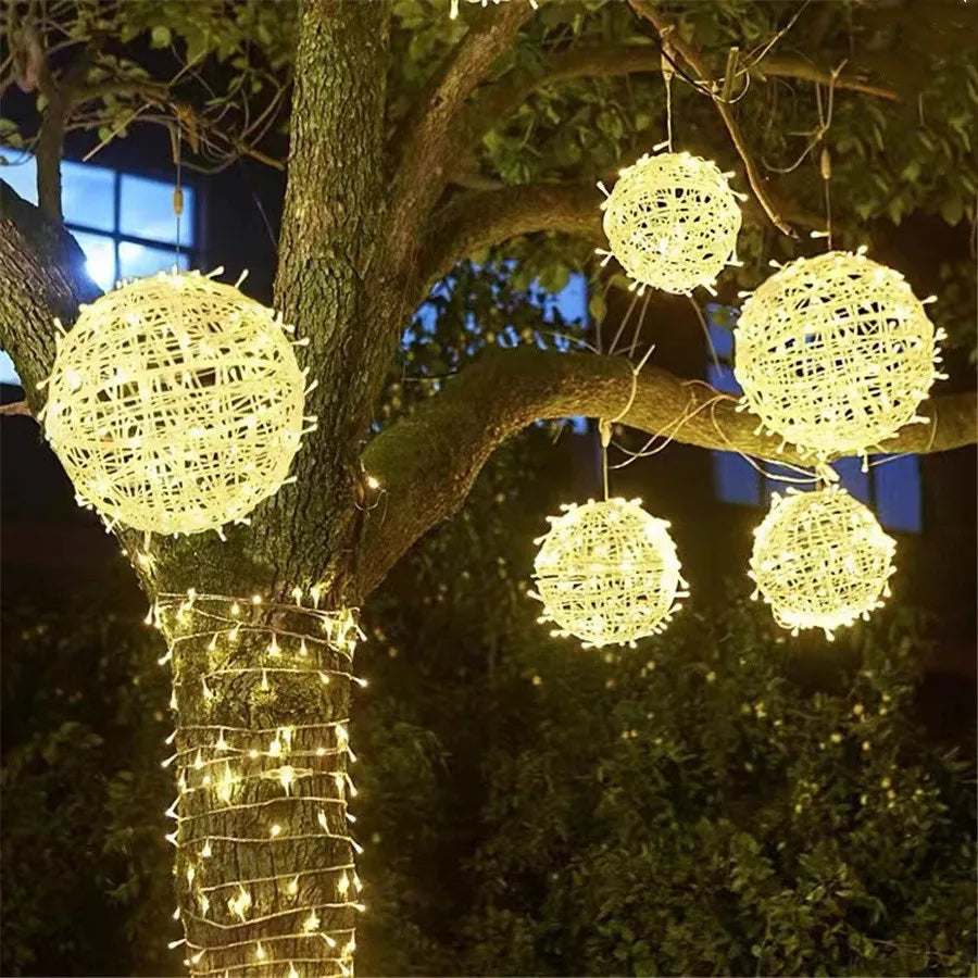 Guirlande lumineuse à boules de rotin tressé allumée dans un jardin